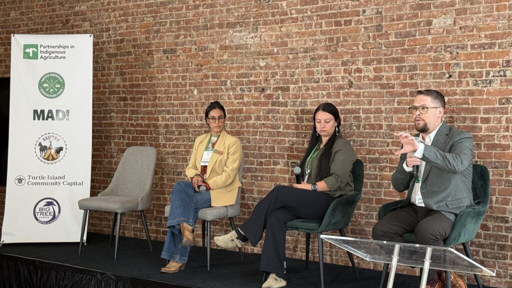 Panelists on stage beside the partner banner at Funding Indigenous Ag Infrastructure